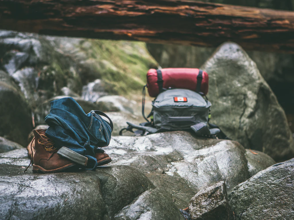 Chaussures de randonnée et sac à dos posés sur des rochers en forêt